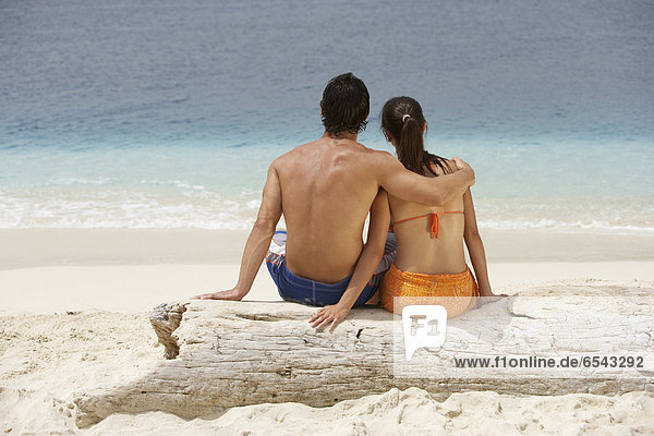 South American couple sitting at beach