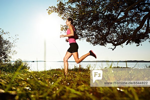 Young woman jogging along lakeshore