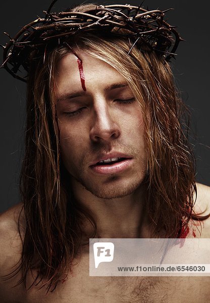 Young man as Jesus wearing crown of thorns  studio shot