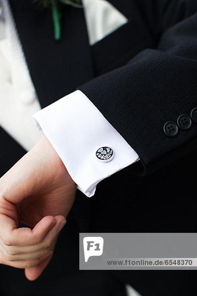 Hand of groom wearing suit and shirt with cuff pins