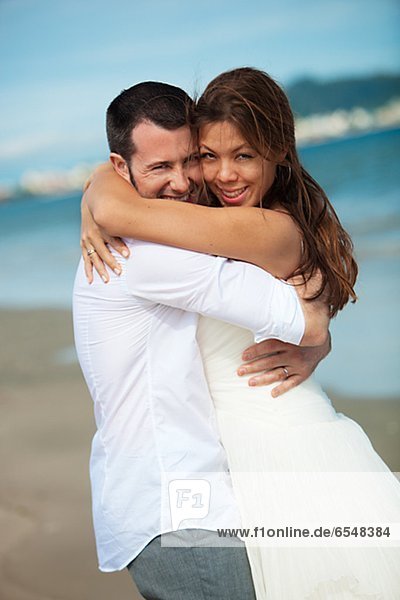Newlyweds embracing on beach