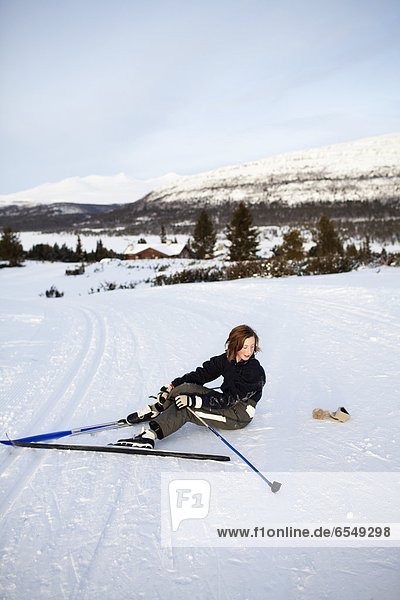 Skier sitting in snow on trail