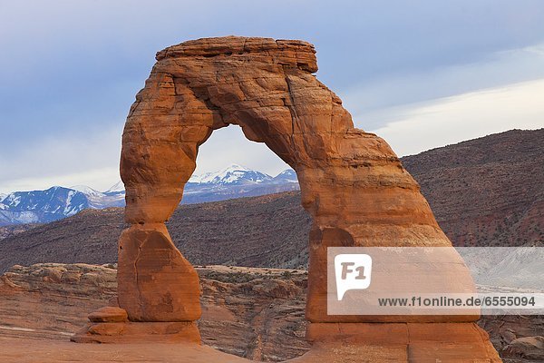 Eroded natural arch  snowcapped mountains in background