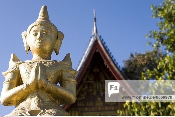Photographer taking pictures of novice monks out collecting alms at dawn.
