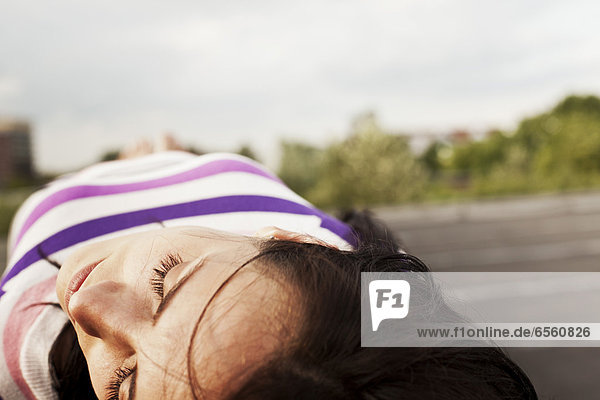 Young woman lying on wall