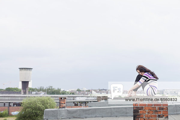Young woman sitting on chimney