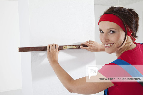 Young woman measuring with spirit level  smiling  portrait