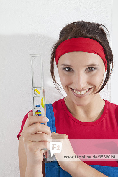 Young woman holding spirit level  smiling  portrait