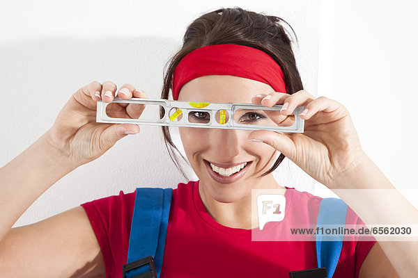 Young woman looking through spirit level