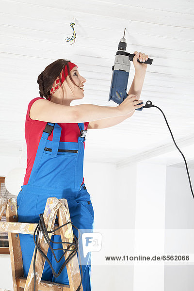 Young woman drilling with electric drill