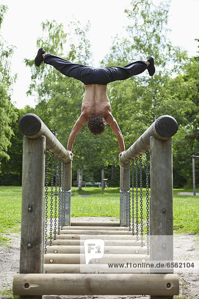 Young man doing handstand on railing