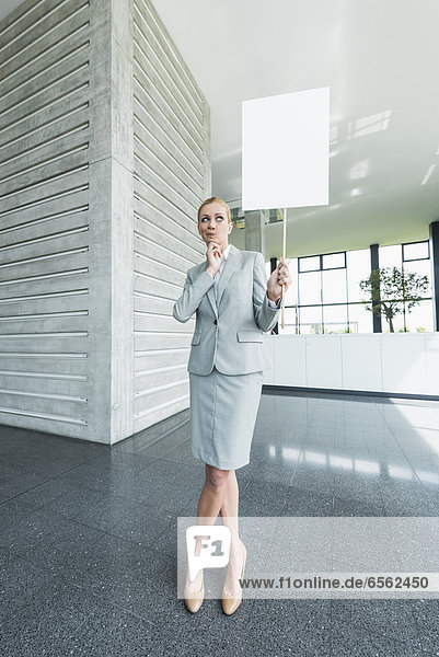 Geschäftsfrau stehend mit leeren Schildern in der Bürolobby