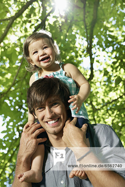 Germany  Cologne  Father carrying daughter on shoulders  smiling