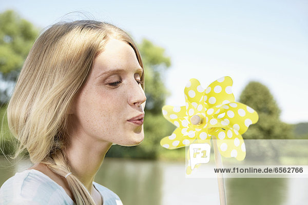Young woman blowing paper windmill