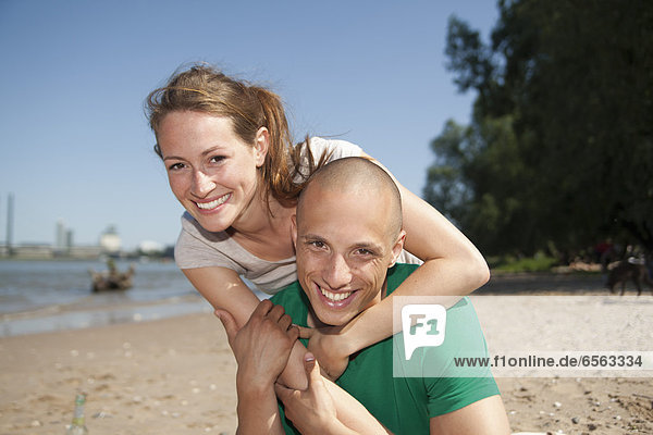Germany  North-Rhine-Westphalia  Duesseldorf  Young couple at beach  portrait  smiling