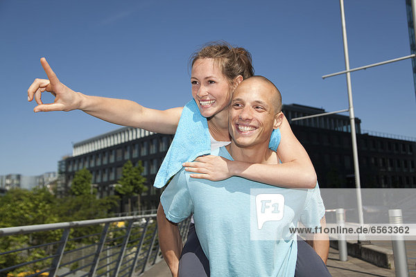 Young man giving piggy back ride to woman