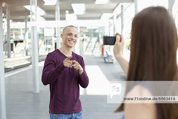 Young woman taking photograph of man