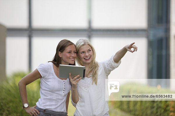 Germany  North Rhine Westphalia  Cologne  Young students with digital tablet  smiling