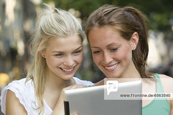 Germany  North Rhine Westphalia  Cologne  Young women using digital tablet  smiling