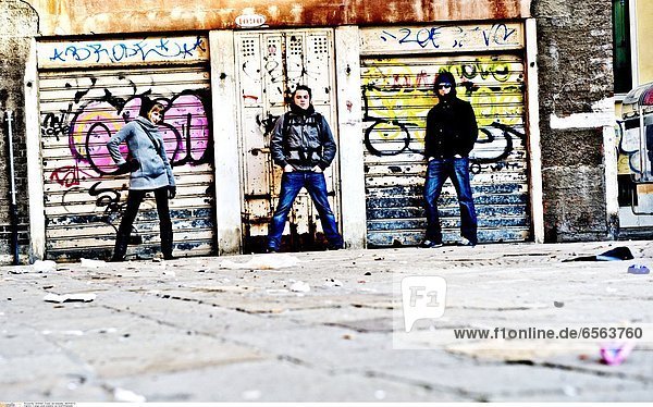 3 junge Leute posieren vor Graffitifassade