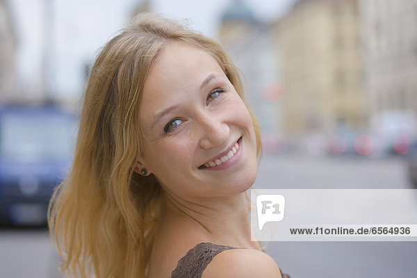 Junge Frau lächelt vor der Staatsbibliothek in der Ludwigstraße