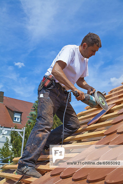 Mid adult man cutting roof tile