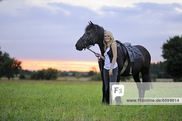 Lächelnde Frau mit Pferd auf einer Wiese