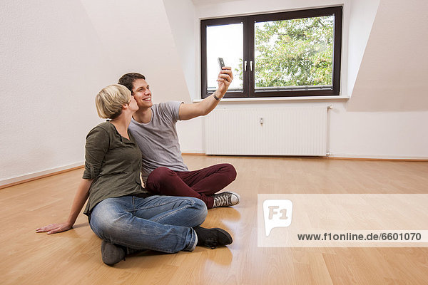 Young couple photographing themselves in a new apartment