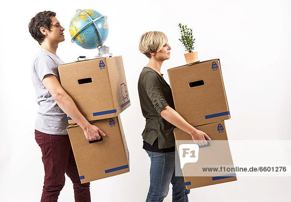 Young couple carrying moving boxes  a globe and a house plant