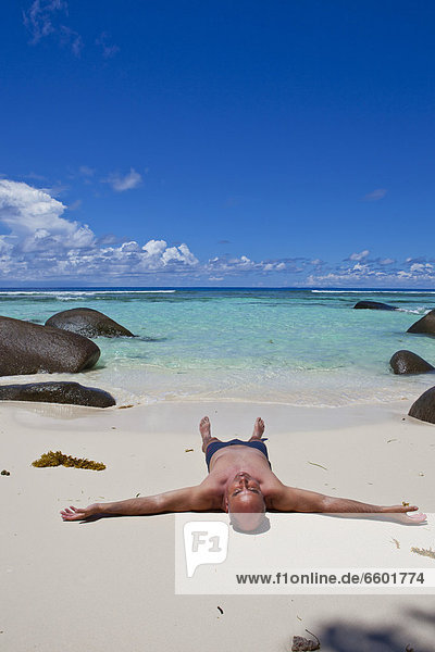 Man lying on a the beach in the sun  Anse La Passe  Silhouette Island  Seychelles  Africa  Indian Ocean