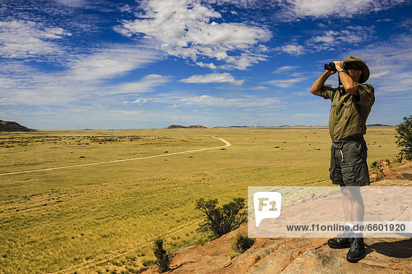 Mann schaut durch Fernglas ins Damaraland  Namibia  Afrika