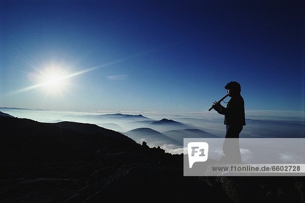 Man Playing Flute Above Mountains