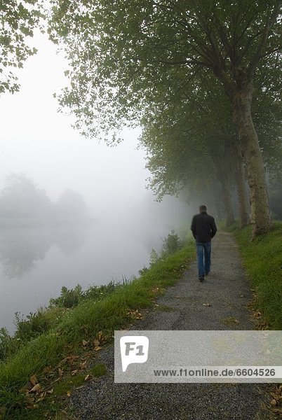 Man Walking Along The Nantes Brest Canal On A Misty Morning