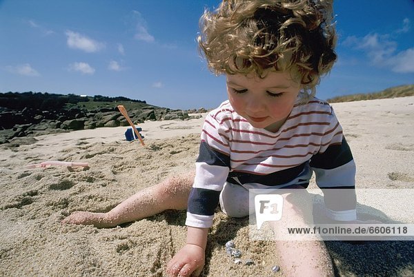 3 Year Old Girl Playing In Sand On Beach In The Scilly Isles