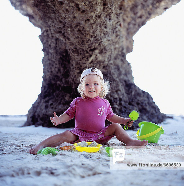 Girls Smiling As She Plays On The Beach With Buckets And Spades