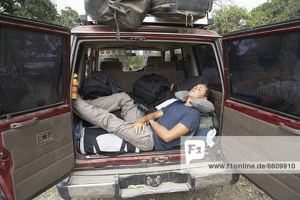 Male Traveler Taking A Nap In The Back Of A 4X4