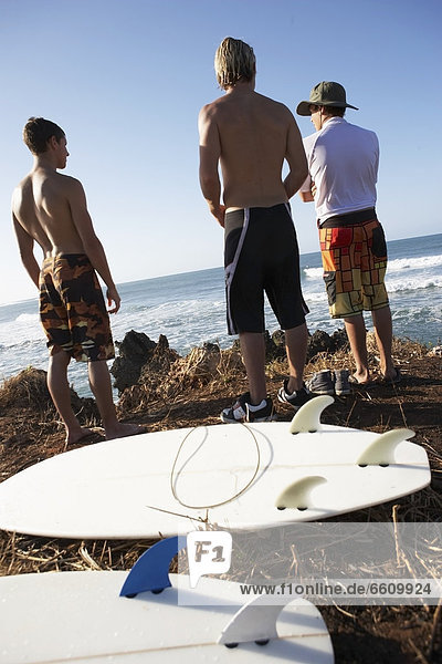 Surfboards On Ground Behind Three Surfers