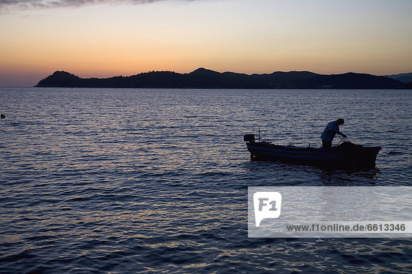 Fisherman in boat at dusk  Lopud Croatia