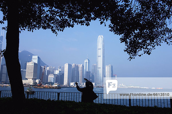 Silhouette of person doing Tai Chi at waterfront park rear view  Hong Kong China