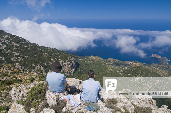 Two people looking at coastline from mountain top rear view  Majorca Balearic Islands Spain