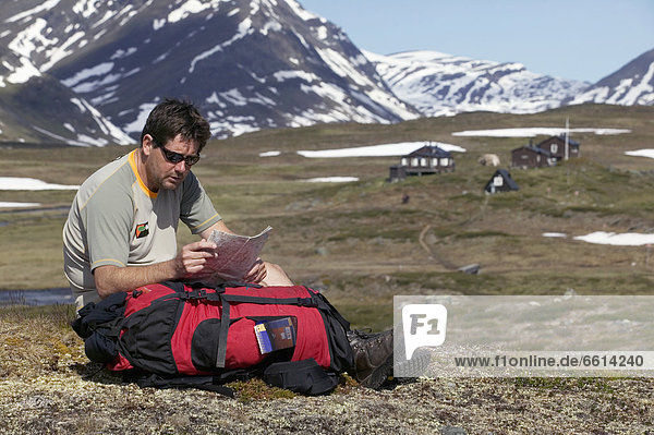 Hiker checking map sitting in valley  Kungsleden trail Abisko Sweden