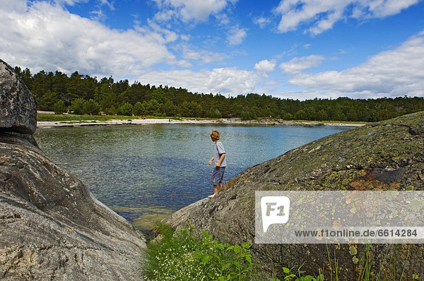Boy (10-11) on rocks on Uto Island  Baltic archipelago off Stockholm Sweden
