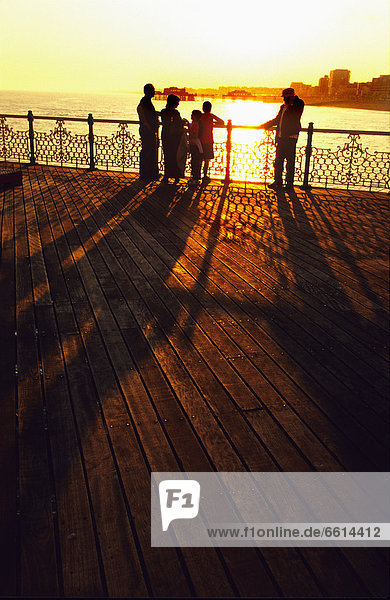 Family watching sunset over city and ocean from Brighton Pier  Brighton UK