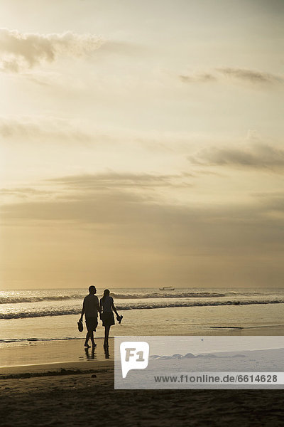 Paar bei Sonnenuntergang am Strand zu Fuß