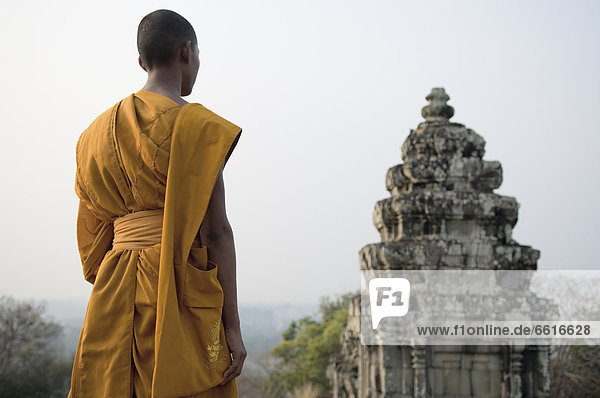 Buddhist Monk Standing Next To Temple On Hill Top  Angkor Wat © Elena Roman Durante / Axiom