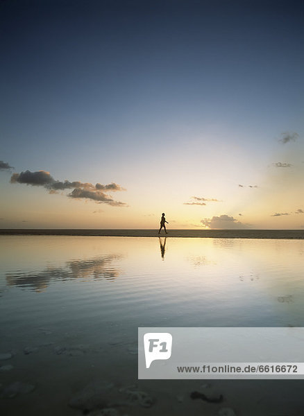 Woman Walking Past Shallow Pool Beside Brighton Beach On West Coast Of Barbados At Dusk. © Ian Cumming / Axiom