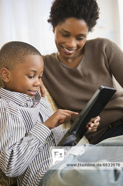 Black mother and son using digital tablet