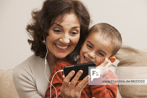 Caucasian grandmother and grandson listening to mp3 player