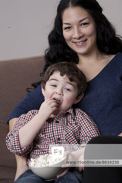 Mixed race mother and son eating popcorn