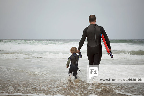 Caucasian father and son preparing to surf together